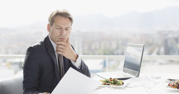 Businessman with lunch reviewing paperwork